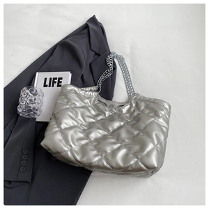 Close-up of silver quilted tote bag featuring metallic chain strap and diamond pattern
