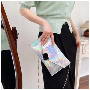 Close-up of silver holographic envelope bag with faux crocodile texture and gold metal buckle