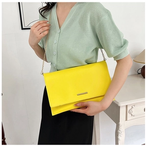 Close-up of bright yellow envelope clutch with gold metal trim and chain strap detail