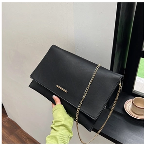Detail of black geometric crossbody bag with gold metal bar and fine chain strap