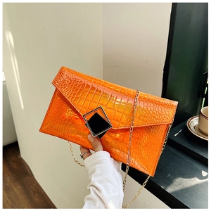 Detail of orange embossed crocodile texture on fashion envelope clutch with chain