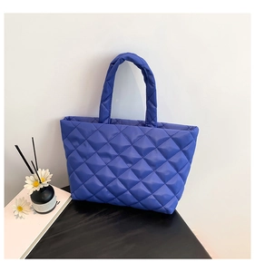 Macro view of navy blue quilted nylon tote bag with rhombus texture and padded handles