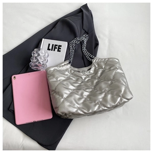 Flat lay of silver quilted tote bag with chain straps next to a stylish grey blazer