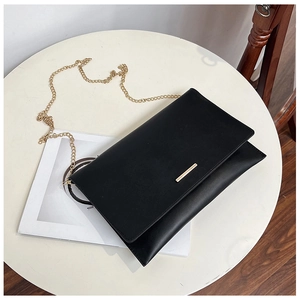 Detail of minimalist black rectangle crossbody bag with gold metal trim and chain strap