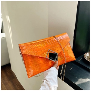 Close-up of bright orange faux crocodile skin texture and gold chain strap of the clutch