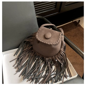 Detail view of dark brown suede saddle bag with fringe tassels in a white box