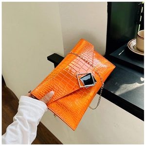 Detail of orange crocodile pattern envelope bag with luxury metal buckle and chain