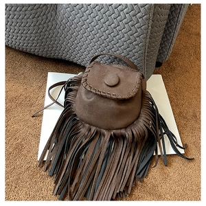 Detailed view of dark brown suede saddle bag with fringe tassels and woven flap