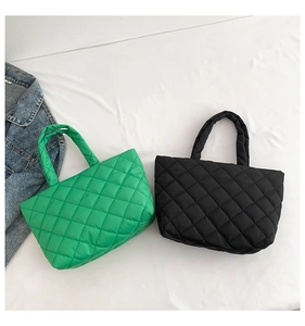 Detail view of green and black quilted tote bags showing thick handles and soft texture