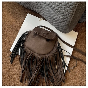 Detail view of brown suede saddle bag featuring woven edges and bohemian fringe accents