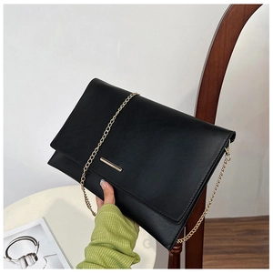 Detail of black envelope clutch featuring gold rectangular hardware and elegant chain strap