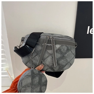 Detail van grijze gewatteerde denim borsttas met ritsen en een mini ronde hanger