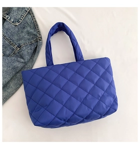 Detailed macro view of bright blue quilted nylon tote bag with classic diamond pattern texture