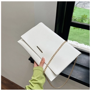 Detail view of a white envelope clutch bag with gold chain and minimalist metal accent