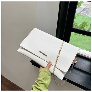 Detail of white leather envelope bag with sleek metal buckle and gold chain strap