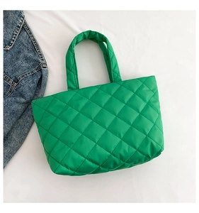 Top view of bright green quilted tote bag with diamond stitching next to denim jacket