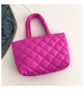 Macro shot of rose red quilted tote bag featuring padded handles and diamond pattern