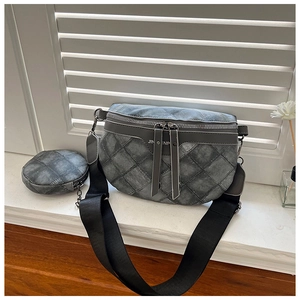 Detail van grijze gewatteerde crossbodytas met denimtextuur en ronde portemonnee-hanger
