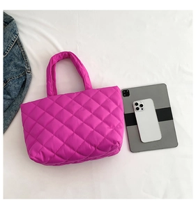 Flat lay of magenta quilted tote bag with tablet and smartphone for size reference