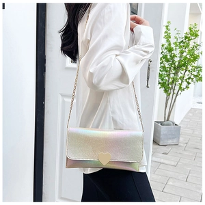 Iridescent metallic shoulder bag with heart clasp worn as a cross-body evening purse