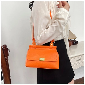 Detail of orange litchi grain leather shoulder bag with gold metal buckle closure