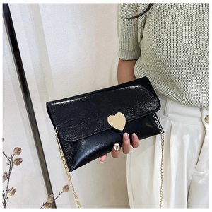 Close-up of black patent leather wallet with a gold heart-shaped lock and chain strap