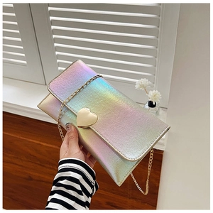 Close-up of holographic metal texture wallet with golden heart lock and chain strap