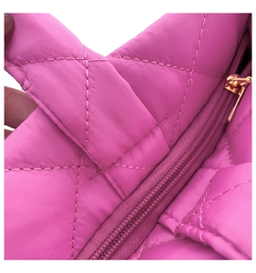 Detail of hot pink quilted nylon tote showing smooth gold zipper and stitched handle texture