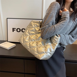 Silver quilted tote bag with diamond pattern and metal chain strap shown on a model