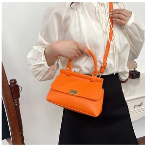 Fashionable orange lychee pattern handbag with golden buckle worn by a model in bright room