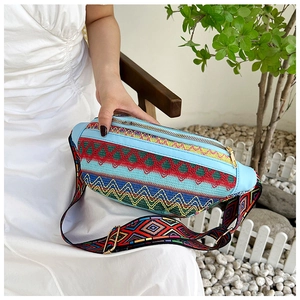 Detail of colorful geometric embroidery and gold zipper on a light blue ethnic waist bag