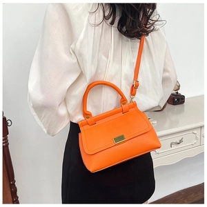 Close-up of orange litchi grain leather texture and gold metal buckle on shoulder bag