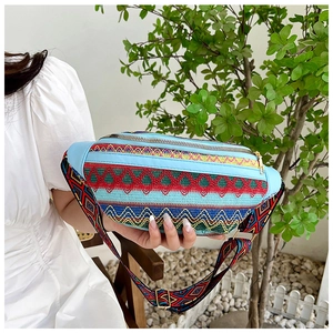 Detailed close-up of bohemian embroidered waist bag with dual gold zippers and floral strap