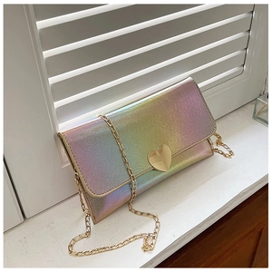 Detailed macro view of laser-textured heart-shaped clasp and gold chain strap on small purse