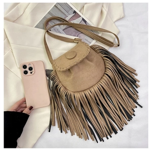 Detailed close-up of khaki faux suede saddle bag with long fringe tassels and golden hardware