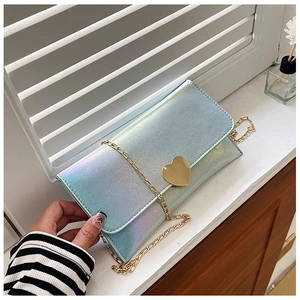 Close-up of holographic blue purse with golden heart buckle and fine metal chain strap