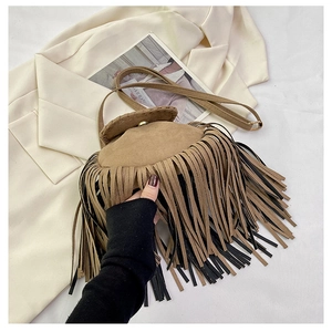 Detailed view of brown suede saddle bag featuring long tassels and gold metal hardware