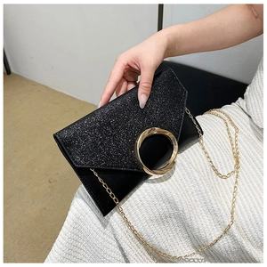 Detail of black envelope clutch with gold ring buckle and sparkling glitter texture