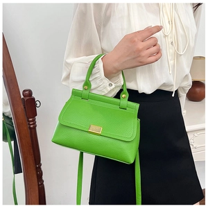 Close-up of bright green litchi texture handbag with gold metal clasp and top handle