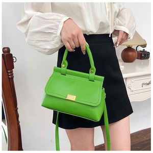 Close-up of green litchi texture leather handbag featuring elegant gold metal buckles
