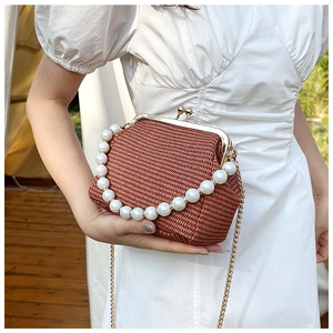 Détail d'un sac tressé en forme de coquillage avec poignée perles et chaîne