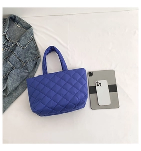 Flat lay of royal blue quilted nylon tote bag with tablet and denim jacket background