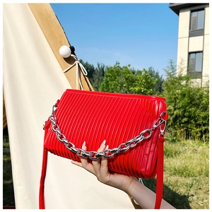 Macro detail of red pleated handbag featuring thick silver chain link and PU leather texture