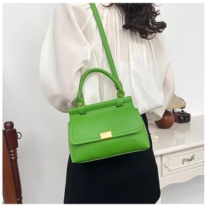 Detailed macro view of bright green litchi texture leather handbag with gold metal lock