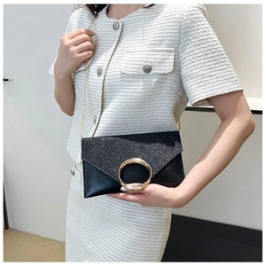 Detail of black envelope clutch featuring large gold metal ring and chain strap