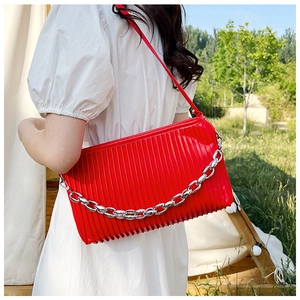 Detail of red pleated shoulder bag with chunky silver chain and leather strap