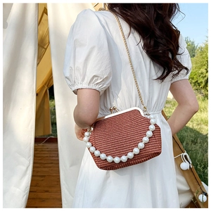 Détail du sac tressé en paille avec poignée en perles et bandoulière chaîne dorée