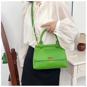 Detailed close-up of a bright green litchi texture leather crossbody bag with gold hardware