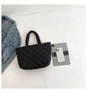 Flat lay of a large quilted tote bag with tablet and phone showing storage capacity