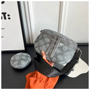 Detail van grijze gewatteerde crossbody borsttas met zilveren rits en nylon schouderriem